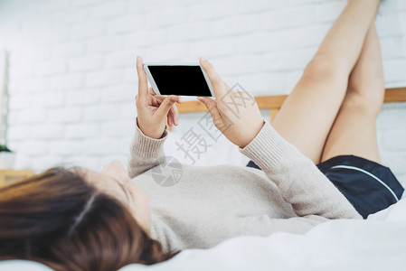 早上在床用黑空白的屏幕使用智能手机在床上用智能手机检查社会应用程序的asin妇女图片