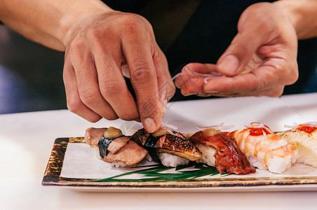 黑体大厨把洋葱切成多种日本寿司黑体在陶瓷板上黑体多头日本寿司上黑体多头日本寿司黑体大虾牛肉图片