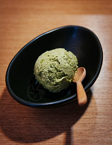 绿色茶冰淇淋黑碗木桌上图片