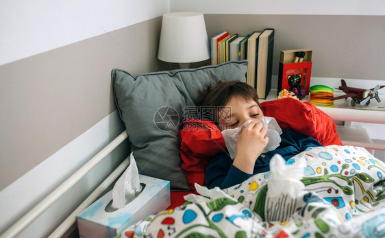 躺在床上的寒冷孩子躺在床上用手帕打他的鼻子图片