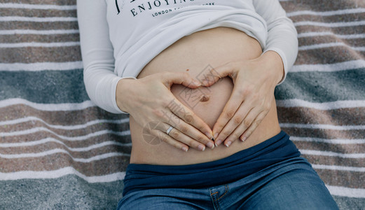 躺在毯子上的孕妇腹部特写图片