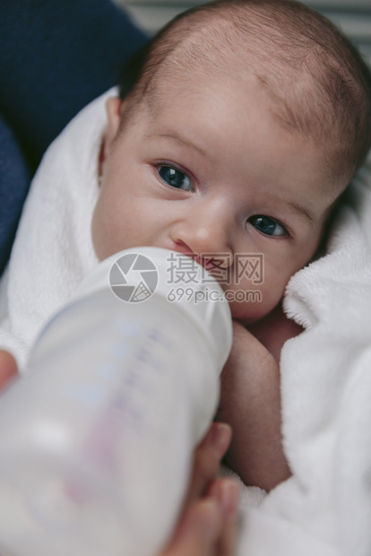 新生女婴在母亲和怀抱中喝着瓶子的奶粉图片