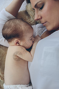 年轻母亲抱着躺在床上的新生女婴图片