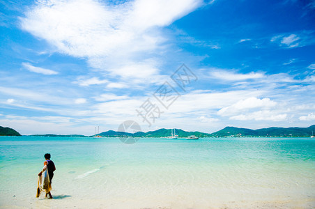 在热带岛屿的海滩上行走渔民在晴朗天空夏图片