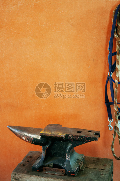 橙色混凝土墙上的旧金属铁板旧匠工具的详情图片