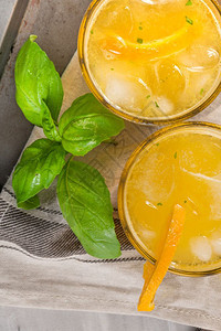 木制橙汁上面装有冰立方体和巴西尔玻璃叶子图片