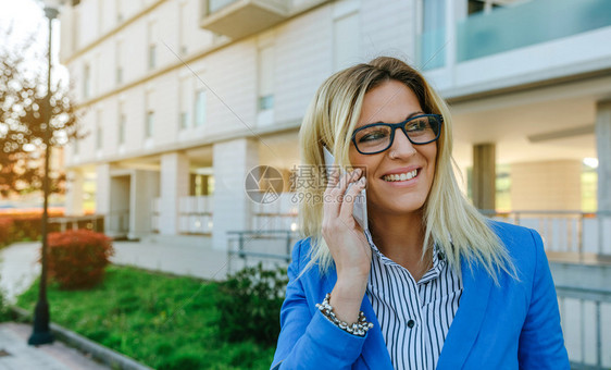 快乐的女商人在街上谈论手机图片