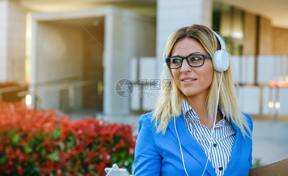 拥有耳机和在街上移动的女商人拥有耳机和移动电话的女商人图片