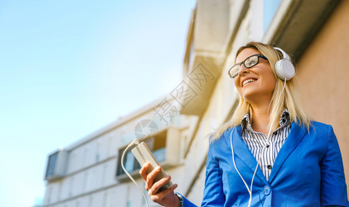 拥有耳机和在街上移动的女商人拥有耳机和移动电话的女商人图片