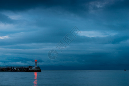 黄昏的海岸上美丽灯塔海上雨云图片