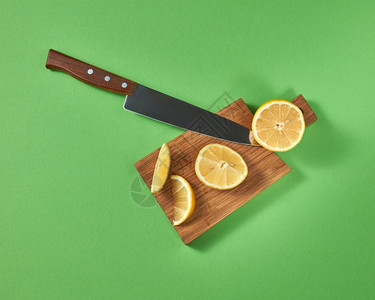 切木板上半片和天然柠檬的顶部有机柑橘水果切开一把锋利的钢刀另一半和块新鲜热带黄柠檬在木制棕色板上用一把钢刀切开从上面看图片