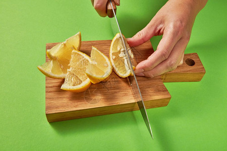 木制棕色板上的柑橘水果用有机成分制天然自柠檬绿色背景的柑橘水果女用手切黄熟柠檬以绿色背景制成自新鲜鸡尾酒图片