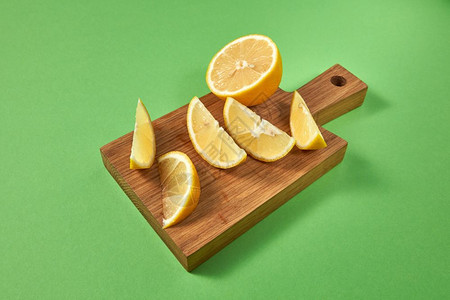 准备天然饮食料的成分绿色背景的木制棕板上柑橘热带柠檬概念健康食物木制棕色板上的半份和片天然有机黄柠檬上面的视图绿色背景的多汁柑橘图片