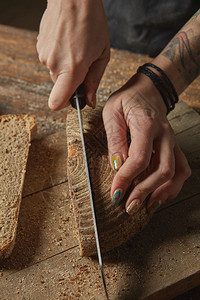 妇女和r手在木制切板上开新鲜烤面包关闭女手切开新鲜烤面包图片