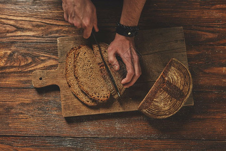 棕色木板上的黑面包一个男人平躺着切面包面包师傅切面包图片