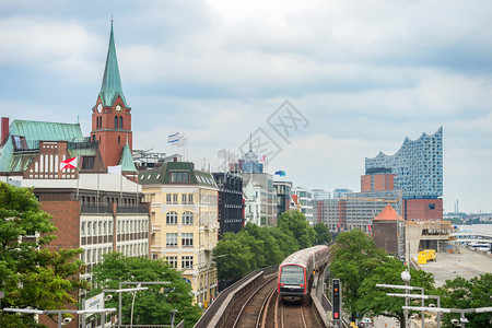 地铁火车经过汉堡的堤岸时钟塔和精灵药店大楼在背景上德国图片