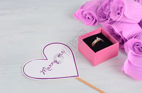粉红盒中的金钻环上面有粉红玫瑰和情人节r以白木背景塑造的心型卡片情人节和日概念图片