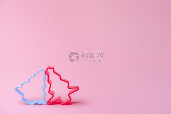 圣诞节甜食的烘烤概念配有两个红蓝的饼干切机紧靠在粉红色纸面背景上图片