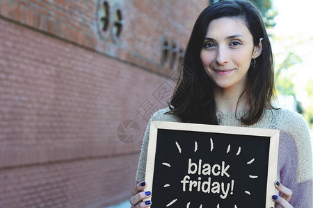 年轻女拿着黑白纸板色星期五的文字销售概念的肖像图片