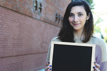 一位年轻美女的肖像坐在黑板上户外图片