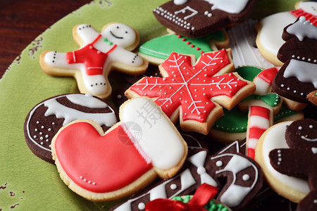 木制桌子上带有彩色圣诞饼干的盘子xmas假日概念图片