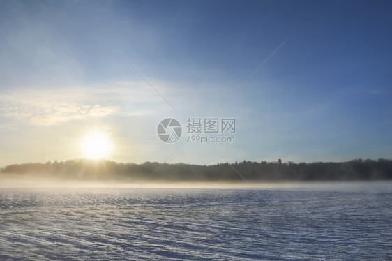 冬季风景日出穿过清晨雾山上一片满是雪的草原图片