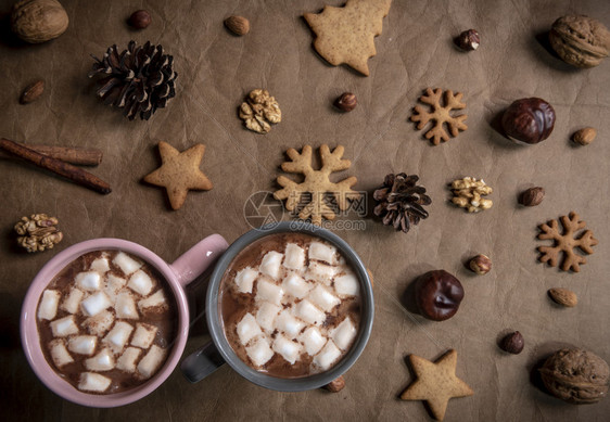 棕色皮革桌毛巾上的冬wes加上松锥和两杯热巧克力迷你棉花糖图片