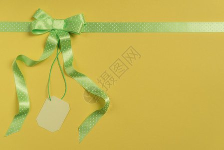 以黄纸包裹的礼品高角度视图有绿色丝带和弓空白标签购物折扣概念礼品背景图片