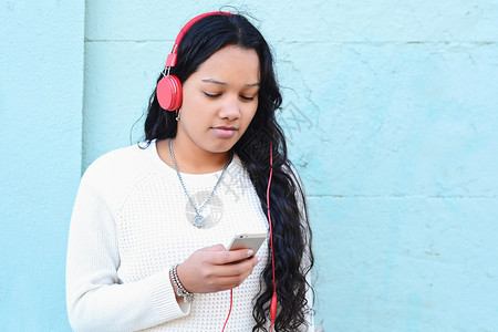 美丽的年轻女子聆听音乐并使用她的智能手机技术概念图片