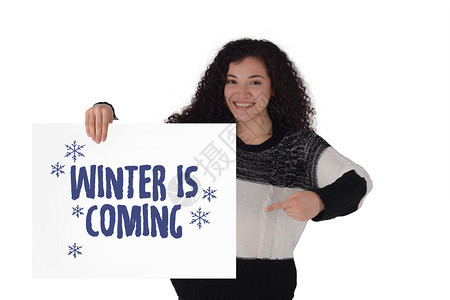 年轻的拉丁女子手持冬天来了的标语文字冬季销售概念孤立的白色背景图片