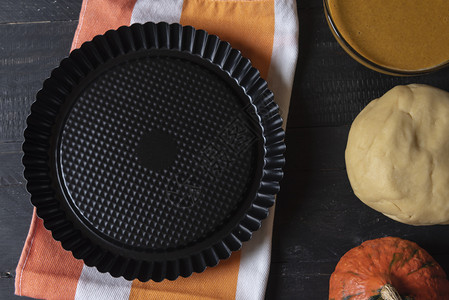 上面是黑铝盘用来烤甜品放在多彩的厨房毛巾和南瓜派面团填料的成分上图片