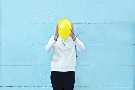 在街上用气球盖着头的年轻女子图片
