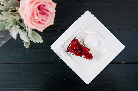 新鲜的樱桃芝士蛋糕粉红色玫瑰从顶部拍摄在黑木桌背景图片