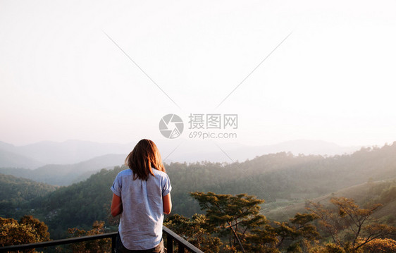 欢喜地庆成功的女人在日落或出站在山顶仰望美丽的山峰图片