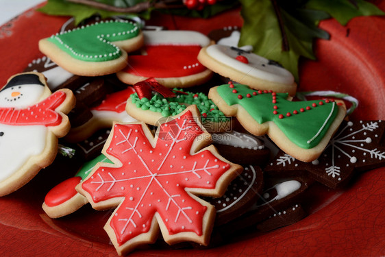 木制桌子上带有彩色圣诞饼干的盘子xmas假日概念图片