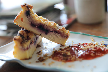 甜点蓝莓奶酪蛋糕在木桌背景上加草莓果酱图片