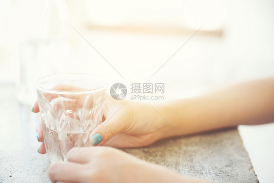 在咖啡店里用手和瓶子在桌上用玻璃和女人的手瓶子装在桌上图片