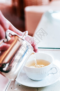 热茶倒入美丽的白瓷杯近距离拍摄图片