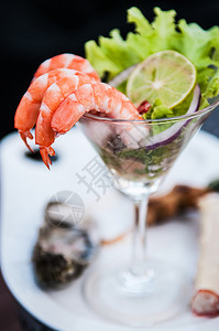 在马提尼杯中近距离拍摄的虾鸡尾酒配有切片石灰和生菜图片