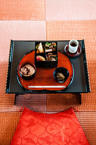 黑色传统日本餐桌和美丽的塔米地板上红色座位垫的便装在黑传统日本餐桌上的便当午图片