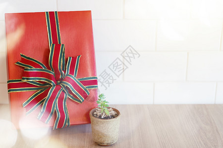 红礼盒紧贴在木桌和白墙上的小树锅可以用于新年快乐圣诞生日和另一个庆祝背景图片