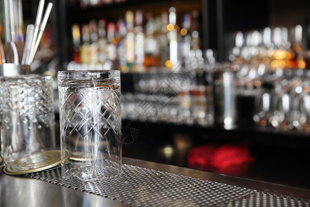 酒吧柜台的威士忌杯子有模糊瓶背景图片