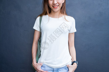 身穿白t恤的棕色长头发亚洲时装女孩站在街上身穿头服装的女站在灰色墙壁背景上图片