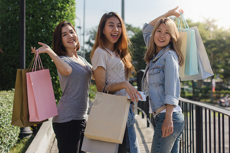 年轻女展示自己在温暖阳光下购物袋中得到的东西图片