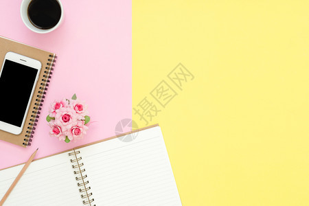 办公桌工作空间平面显示工作空间的顶部有白笔记本页咖啡杯和糊面背景模拟电话粉色彩背景空间概念图片