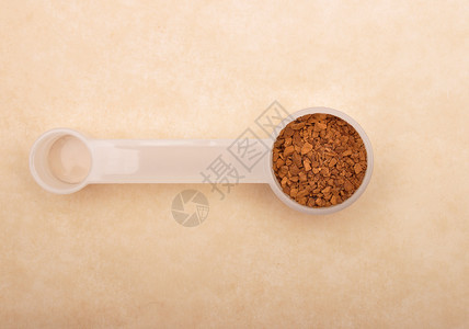 棕色背景上测量勺子的速快咖啡图片