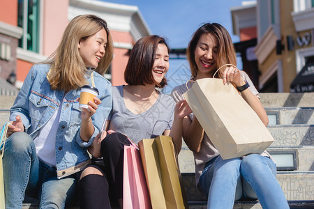 年轻女展示自己在温暖阳光下购物袋中得到的东西图片