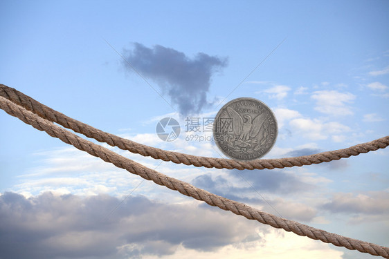 一美元硬币在天空的绳子上平衡图片