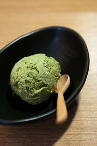 绿色茶冰淇淋黑碗木桌上图片