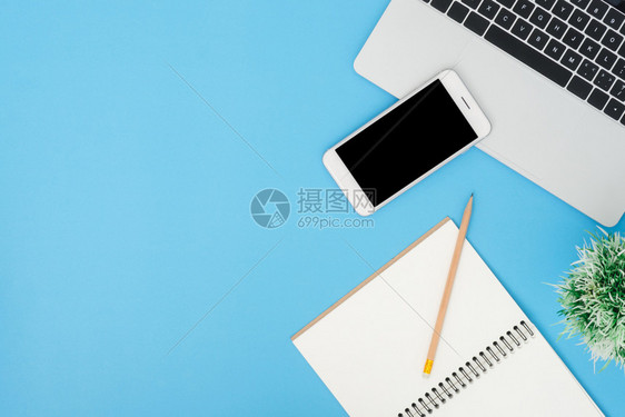 办公桌工作空间平面工作空间模拟照片用笔记本电脑智能手机和空白笔记本拍摄在蓝面背景上部蓝色背景工作桌概念图片